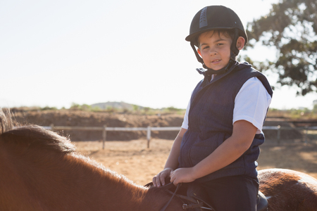 Boy riding a horse in the ranch on a sunny dayの写真素材