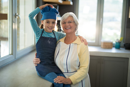 Grandmother and granddaughter posing by embracing each other in the kitchenの写真素材