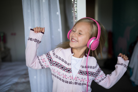 Close-up of girl listening to music on headphones at homeの写真素材
