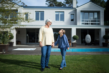 Smiling granddaughter and grandmother standing in garden on a sunny dayの写真素材