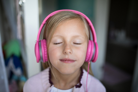 Close-up of girl listening to music on headphones at homeの写真素材