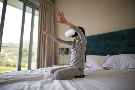 Girl using virtual reality headset on bed in bedroomの写真素材