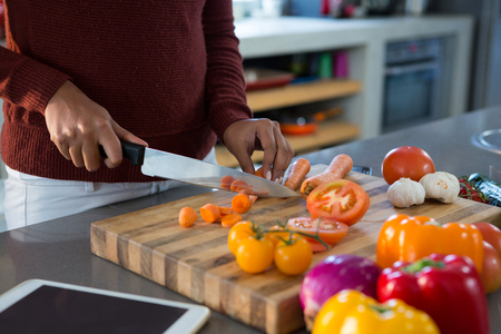 Mid section of woman cutting vegetables at kitchen counterの写真素材