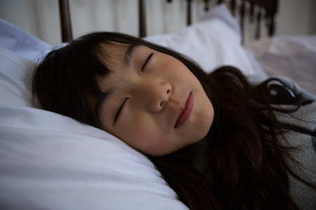 Girl sleeping on bed at homeの写真素材