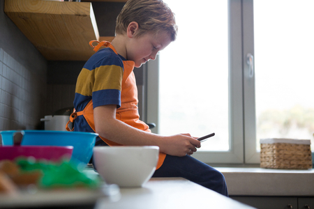 Side view of boy using digital tablet at kitchen counterの写真素材