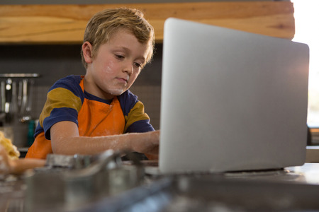 Boy using laptop at kitchen counterの写真素材