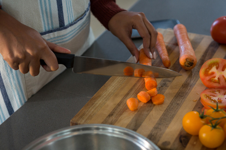 Mid section of woman cutting carrot in kitchen at homeの写真素材