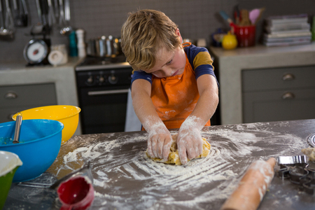 Boy kneading dough at counter in kitchenの写真素材
