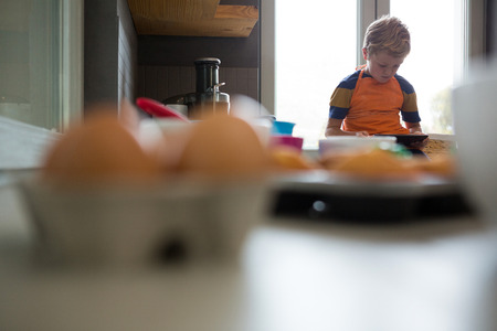 Boy using tablet while sitting at kitchen counterの写真素材