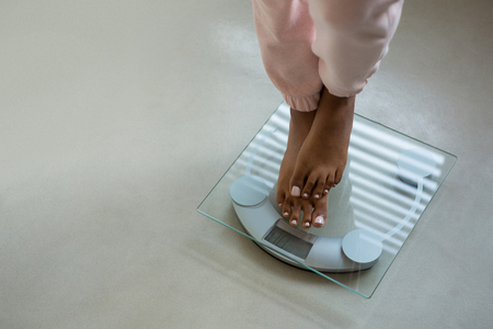 Low section of woman standing on bathroom scale at homeの写真素材