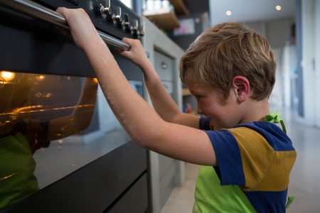 Smiling boy looking at oven in kitchenの写真素材