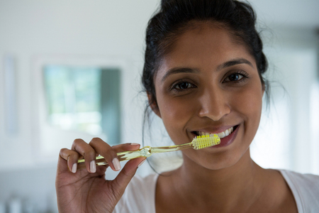Portrait of woman brushing teeth in bathroom at homeの写真素材