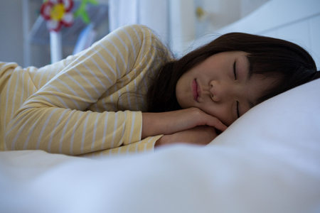Innocent girl sleeping on bed at homeの写真素材
