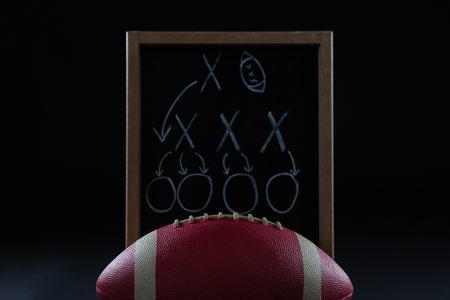 Close-up of American football and game strategy drawn on board against black backgroundの写真素材