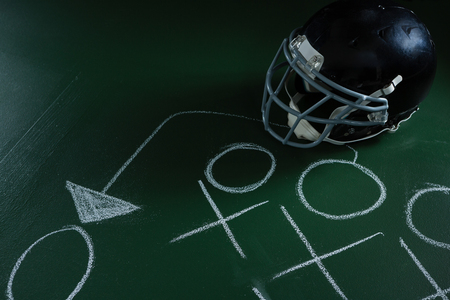 Close-up of American football head gear lying on green board with strategy drawn on itの写真素材