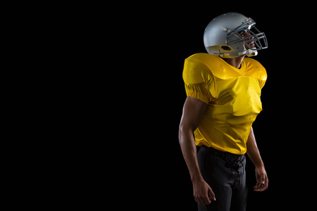 American football player standing against a black backgroundの写真素材