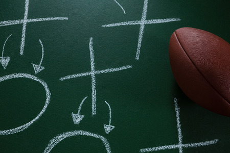Close-up of American football lying on green board with strategy drawn on itの写真素材