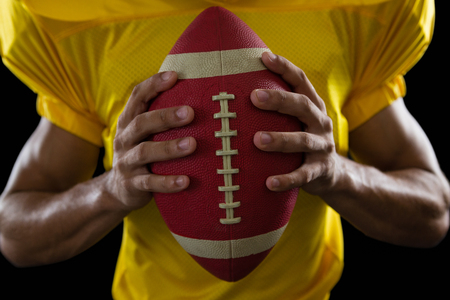 Mid section of American football player holding a ballの写真素材