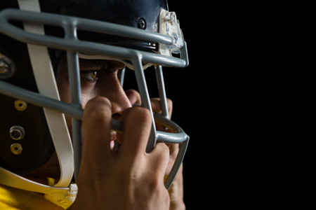 Mid section of American football player holding a head gear on his headの写真素材