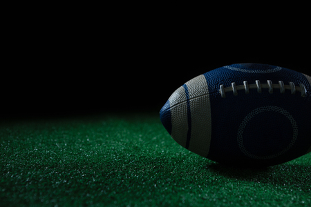 Close-up of American football on artificial turf against black backgroundの写真素材
