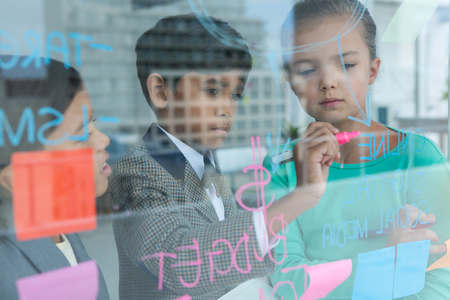 Business people discussing while writing on window seen through glass at office