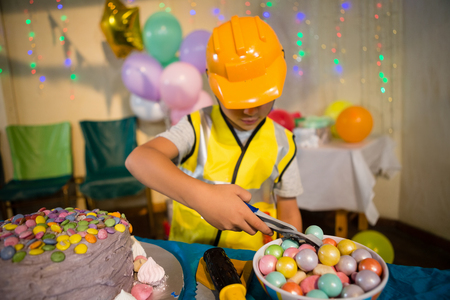 Cute boy pretending to be a worker while decorating birthday cake