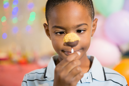 Cute boy holding lollipop during birthday party at homeの写真素材