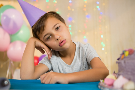 Portrait of boy sitting near a birthday cake at home