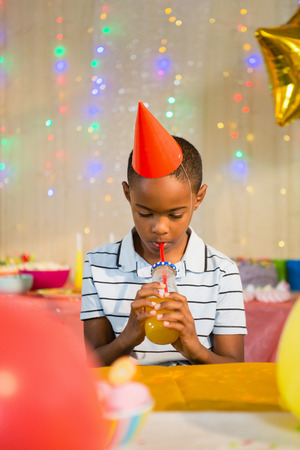 Boy drinking juice during birthday party at homeの写真素材