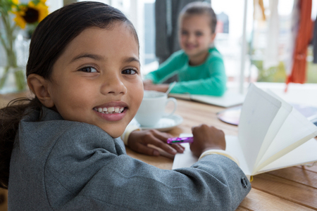 Portrait of smiling businesswoman writing while sitting at table in creative officeの写真素材