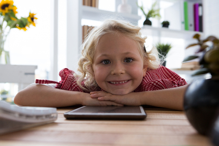 Portrait of happy businesswoman with tablet computer relaxing on table in creative officeの写真素材