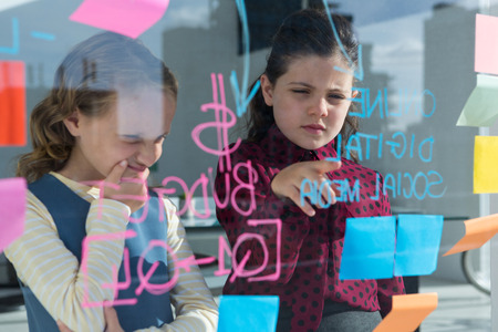 Female coworkers anlayzing data at creative office seen through glass