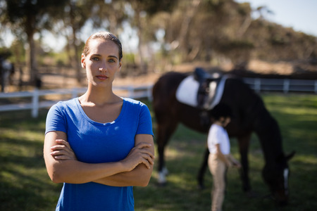 Portrait of young female jockey with sister by horse in background at paddockの写真素材