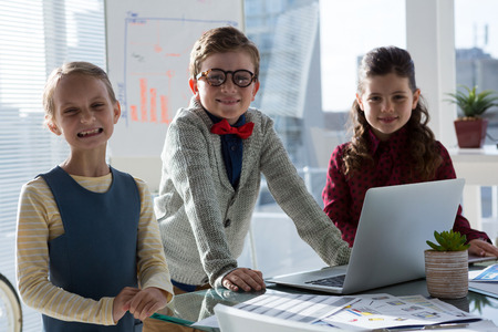 Portrait of smiling business people standing at table in officeの写真素材