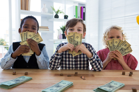 Portrait of business people with currency standing at table in creative officeの写真素材
