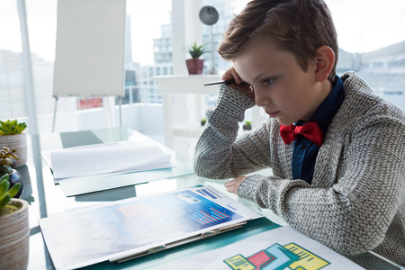 Close up of businessman reading documents while sitting at desk in office