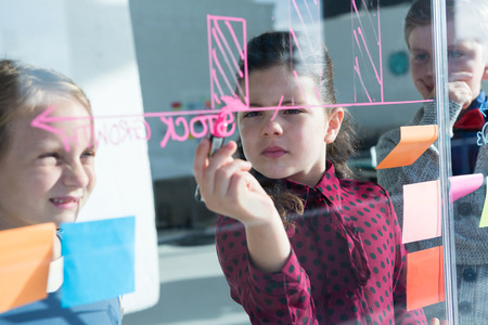 Businesswoman explaining graph to coworkers at creative office seen through glass