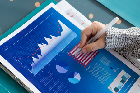 Cropped hand of businessman analyzing data at table in officeの写真素材