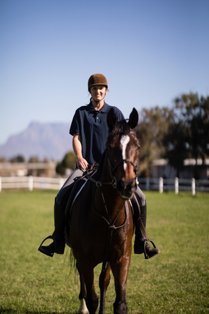 Portrait of confident female jockey riding horse at barnの写真素材