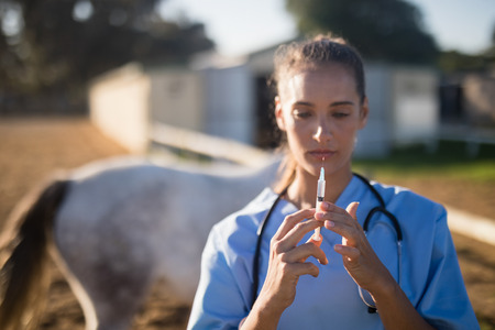 Close up of female vet holding syringe at barnの写真素材