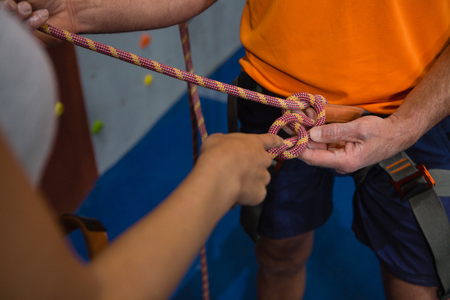 Cropped hand of woman typing harness of man in gymの写真素材
