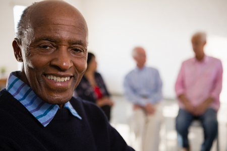 Close up Portrait of smiling senior man with friends in background at art classの写真素材
