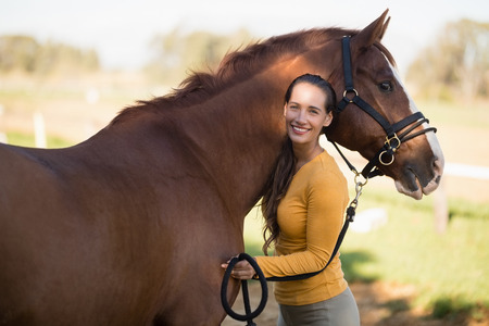 Portrait of female jockey standing by horse at barnの写真素材