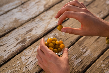 Cropped hand holding winter cherry at wooden tableの写真素材