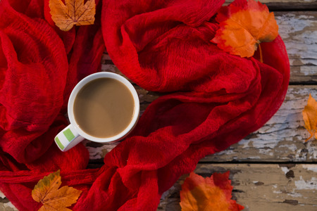 Overhead view of coffee cup amidst scarf on wooden tableの写真素材