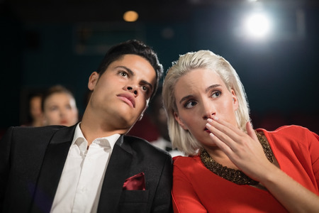 Happy couple watching movie in theatreの写真素材