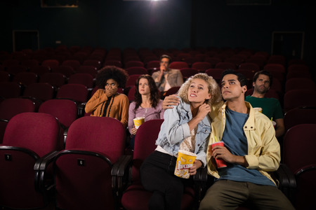 Happy couple watching movie in theatreの写真素材