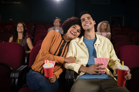 Mid-section of couple watching movie in theatreの写真素材