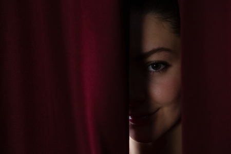 Happy ballet dancer peeking through a stage curtainの写真素材