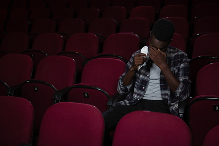 Man getting emotional while watching movie in theatreの写真素材